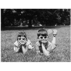  Two Children Lie on the Grass in a Park Each Sporting a 