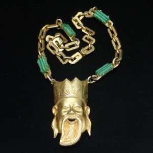 Large goldtone Asian face with long beard and crownlike hat hangs from 